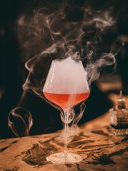 Ein rauchiger Cocktail in einem eleganten Glas, serviert auf einem Tisch im Restaurant Veranda.