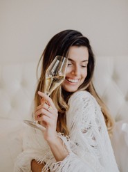 Lächelnde Frau mit einem Glas Sekt in der Hand in hellem Ambiente im Restaurant Veranda.
