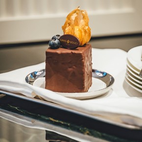 Eine Schokoladentorte mit dem Sans Souci Logo und Früchten auf einem Teller im Restaurant Veranda.