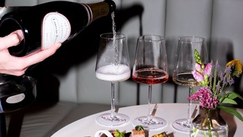 Champagner wird in Weingläser eingeschenkt, neben Canapés und einem Blumenstrauß.