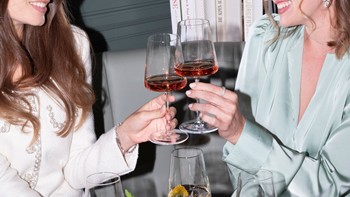 Zwei Frauen stoßen mit Champagnergläsern an, während sie im Veranda Restaurant sitzen.