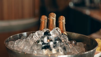 Drei Flaschen Champagner liegen in einem Eiskübel, umgeben von Eiswürfeln.