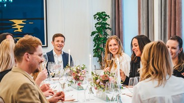 A group of people are sitting at a table decorated with flowers and candles.