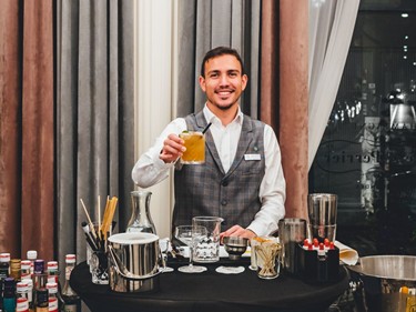 Ein Barkeeper zeigt stolz einen Cocktail, während er an einer Cocktailbar steht.