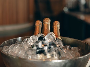 Drei Flaschen Champagner liegen in einem Eiskübel, umgeben von Eiswürfeln.