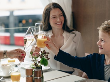 A family cheers with champagne and orange juice at breakfast.
