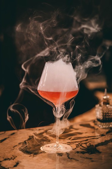 Magical moments at our cocktail classes A smoky cocktail in an elegant glass, served on a table at Veranda Restaurant.