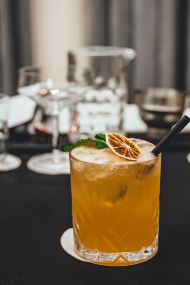 Learn the art of cocktail mixing A cocktail with citrus fruits and herbs is served on a table.