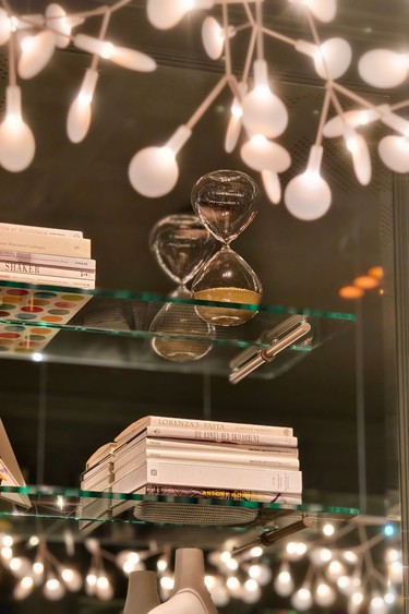 Eine elegante Regaleinrichtung mit einer Sanduhr und warmem Licht im Hintergrund.