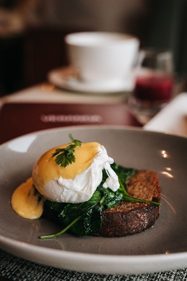 Pochiertes Ei mit Sauce Hollandaise, Spinat und geröstetem Brot auf einem Teller im Restaurant Veranda.