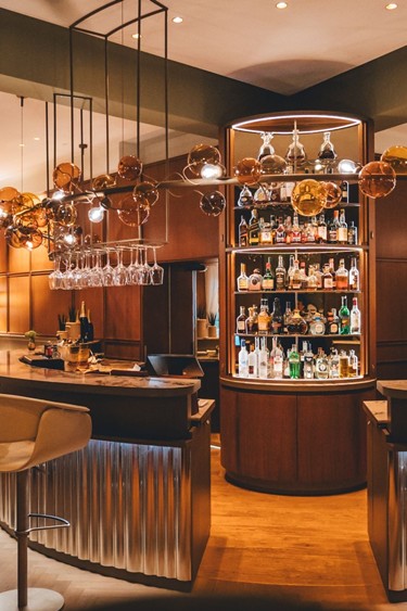 Blick auf die Bar im Restaurant Veranda mit eleganter Beleuchtung und einer Auswahl an Spirituosen.