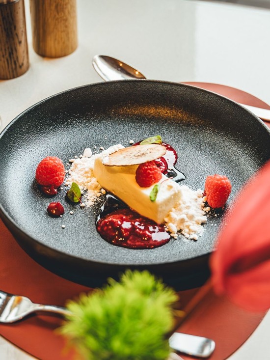 Feines Dessert mit Himbeeren und Fruchtsauce kunstvoll angerichtet in der Veranda Brasserie & Bar.