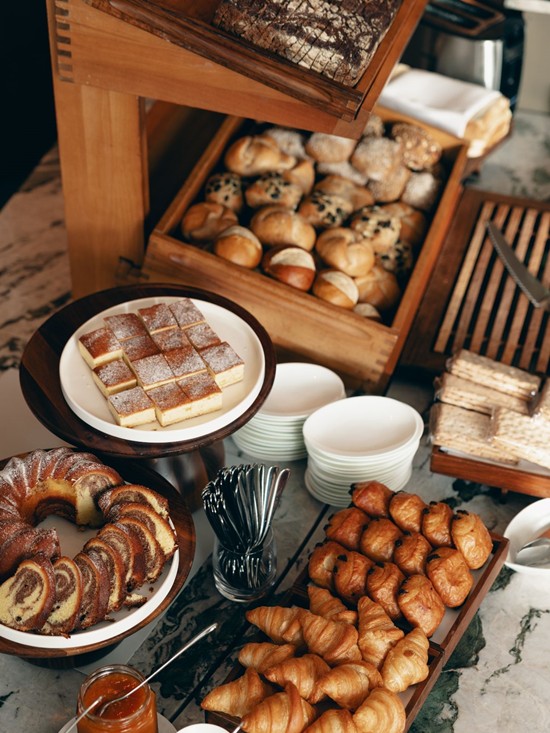 Ein Frühstücksbuffet mit frischen Brötchen, Kuchen und Marmelade im Restaurant Veranda.