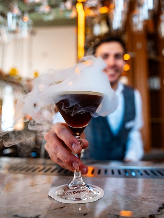 Bartender serviert ein rauchendes Cocktailglas im Restaurant Veranda.