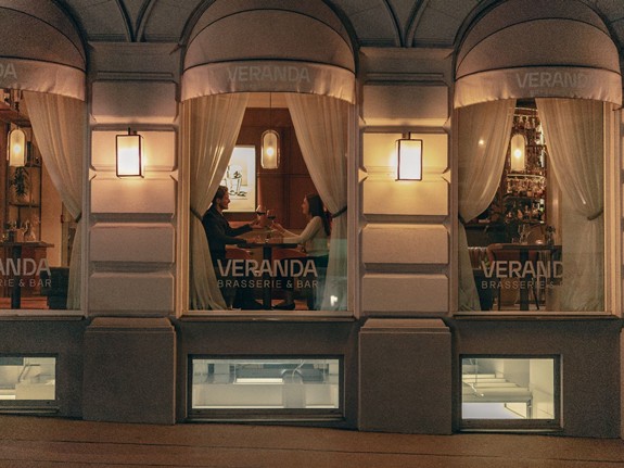 Zwei Personen stoßen mit Cocktails an, während sie im Veranda Restaurant sitzen.